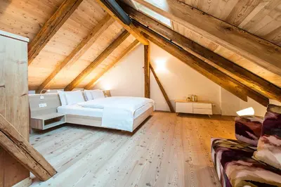 a bedroom with a white bed in a attic at Hofbauer in Brunico
