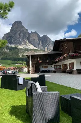 a resort with a table and chairs and a mountain at Apartments La Vara in Corvara in Badia