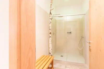 a bathroom with a shower and a wooden bench at Unterthurnerhof in Rifiano