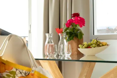 a glass table with vases and a bowl of grapes and flowers at MeranoView Apartments in Marlengo