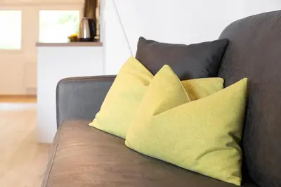two yellow pillows sitting on a gray couch at MeranoView Apartments in Marlengo