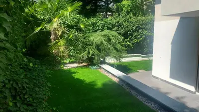 a garden with green grass and trees and a building at Villa Romana Meran in Merano