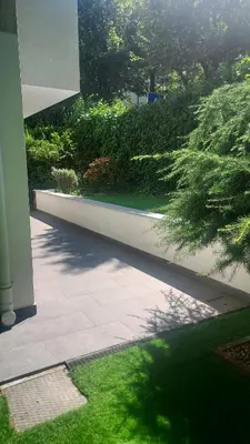 a patio with grass and bushes and a building at Villa Romana Meran in Merano