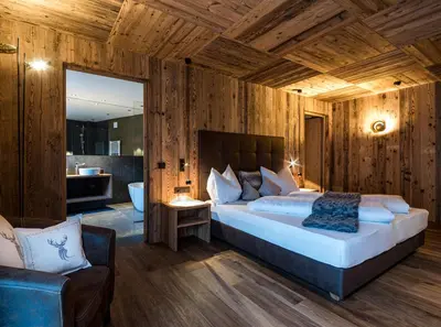 a bedroom with a large bed and a chair at Mi Coa in Santa Cristina in Val Gardena