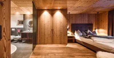 a bedroom with a large bed and a bathroom at Mi Coa in Santa Cristina in Val Gardena
