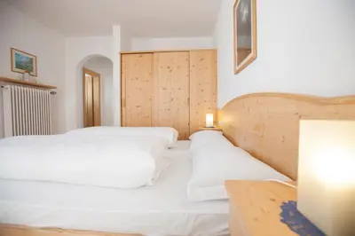 a bedroom with two white beds and a table at Residence Bergblick in Bressanone