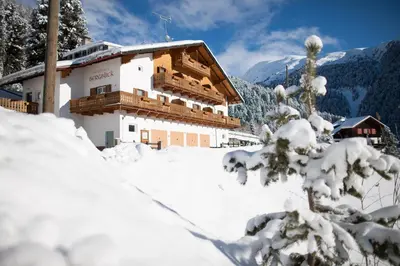 a building covered in snow next to a mountain at Residence Bergblick in Bressanone
