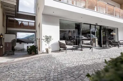 a patio of a building with chairs and windows at Alpin & Stylehotel Die Sonne in Parcines