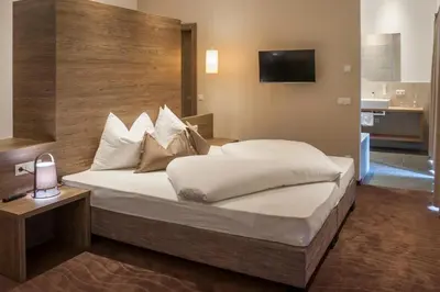 a bedroom with a large bed and a television at Hotel Rosengarten in Nova Levante