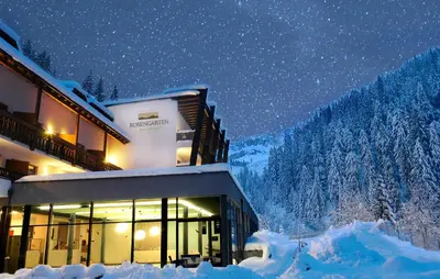 a building covered in snow at night at Hotel Rosengarten in Nova Levante