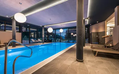 a swimming pool in a building with a house at Hotel Rosengarten in Nova Levante