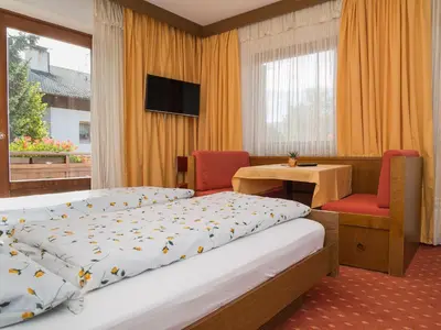 a hotel room with a bed and a table and chairs at Haus Elisabeth in Nova Ponente