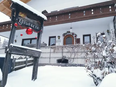 a house covered in snow with a sign in front at Haus Elisabeth in Nova Ponente