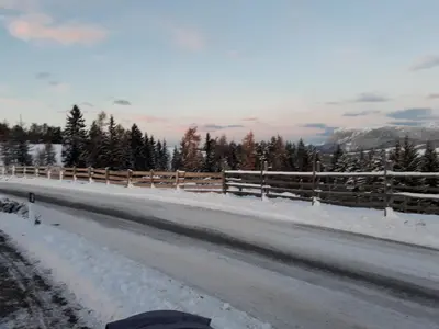 a road covered in snow with a fence and trees at Haus Elisabeth in Nova Ponente
