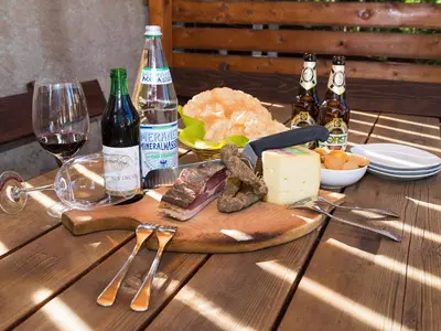 a table with a plate of meat and cheese and bottles of wine at Haus Elisabeth in Nova Ponente