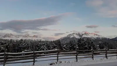 a fence in front of a snow covered mountain at Haus Elisabeth in Nova Ponente