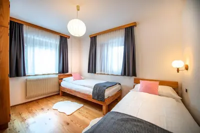 a bedroom with two beds and two windows at Apartment Sellablick in Ortisei