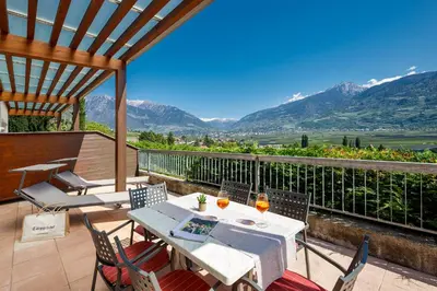 a table and chairs on a balcony with mountains at Ferienhaus Törggelehof in Cermes