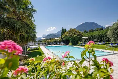 a pool with pink flowers and mountains in the background at Ferienhaus Törggelehof in Cermes