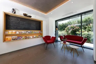 a waiting room with red chairs and a chalkboard at Ferienhaus Törggelehof in Cermes