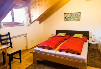 a bedroom with a large bed with red sheets at Birbamergut in Longomoso