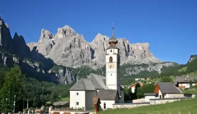 a building with a clock tower in front of a mountain at Saina in Colfosco