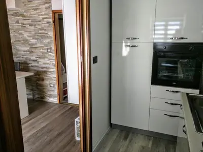 a kitchen with white cabinets and a stove at Regina del Bosco della vicina Cavalese in Daiano