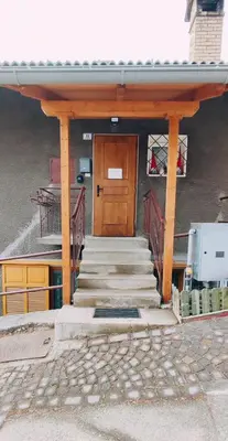 a building with a wooden door and stairs in front at Regina del Bosco della vicina Cavalese in Daiano