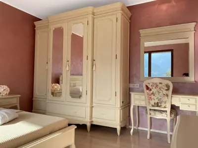 a bedroom with a large white cabinet and a chair at VILLA COLLINA VERDE in Bolzano