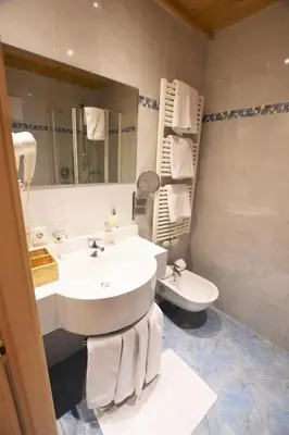 a bathroom with a sink and a toilet and a mirror at Residence Palmai in Ortisei