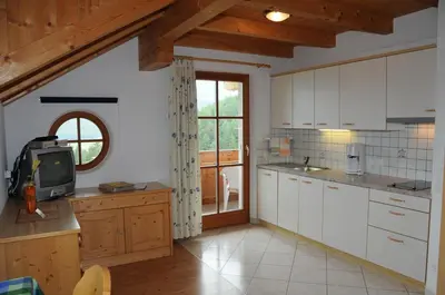 a kitchen with white cabinets and a tv in it at Zangerlechnhof in Brunico