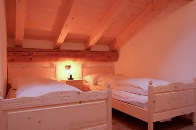 two white beds in a room with wooden ceilings at La Rocia 2 in Rocca Pietore