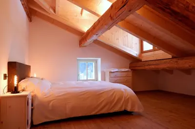 a bedroom with a white bed and wooden ceilings at La Rocia 2 in Rocca Pietore