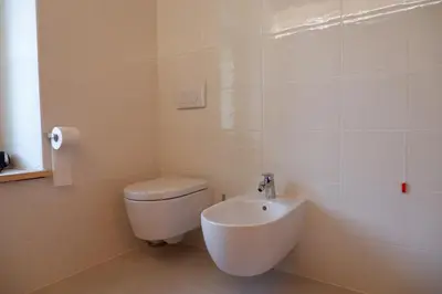 a white bathroom with a toilet and a sink at La Rocia 2 in Rocca Pietore