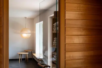 a glass door leading into a wine cellar with a table and stool at Kronplatz Ski Lodge in Valdaora