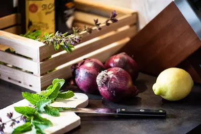 a table with onions and a knife and a cutting board at Kronplatz Ski Lodge in Valdaora