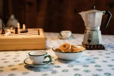 a table with a cup of coffee and a bowl of cookies at Kronplatz Ski Lodge in Valdaora
