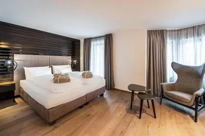 a bedroom with a large bed and a chair at Stella Hotel - My Dolomites Experience in Selva di Val Gardena