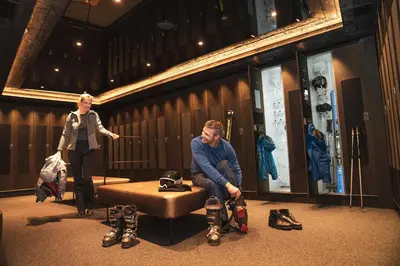 a woman standing next to a man wearing boots in a room at Stella Hotel - My Dolomites Experience in Selva di Val Gardena