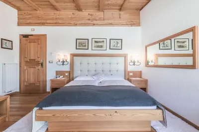 a bedroom with a large bed and a mirror at Almhotel Col Raiser in Santa Cristina in Val Gardena