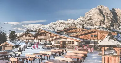 a lodge with tables and chairs in the snow at Almhotel Col Raiser in Santa Cristina in Val Gardena