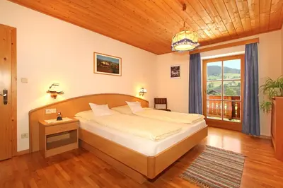 a bedroom with a large bed with a wooden ceiling at Peternaderhof in Vols am Schlern
