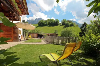 a yard with two chairs and an umbrella at Peternaderhof in Vols am Schlern