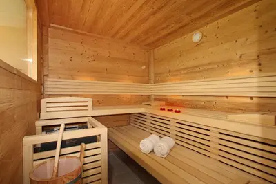 a sauna with wooden paneling and towels on shelves at Peternaderhof in Vols am Schlern