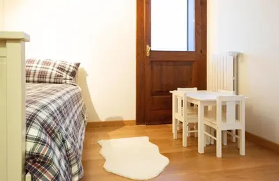 a room with a bed and a table and a door at Chalet Ruoibes in San Vito di Cadore