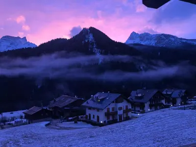 a group of houses in the snow with a mountain at Chalet Ruoibes in San Vito di Cadore