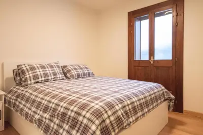 a bedroom with a bed with a plaid blanket and a window at Chalet Ruoibes in San Vito di Cadore