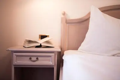 a book on a night stand next to a bed at Ebnerhof in Appiano sulla Strada del Vino