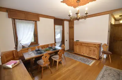 a dining room with a table and chairs and a chandelier at Punta Nera: appartamento con giardino e WIFI in Zuel