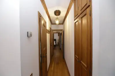 a long hallway with a ceiling and white walls and wooden doors at Punta Nera: appartamento con giardino e WIFI in Zuel